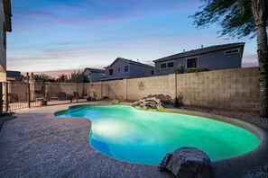 Een buitenzwembad, ligstoelen bij het zwembad