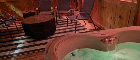 Puinen spa-huone, jossa on poreallas, oleskelualue ja ruukussa oleva kasvi.