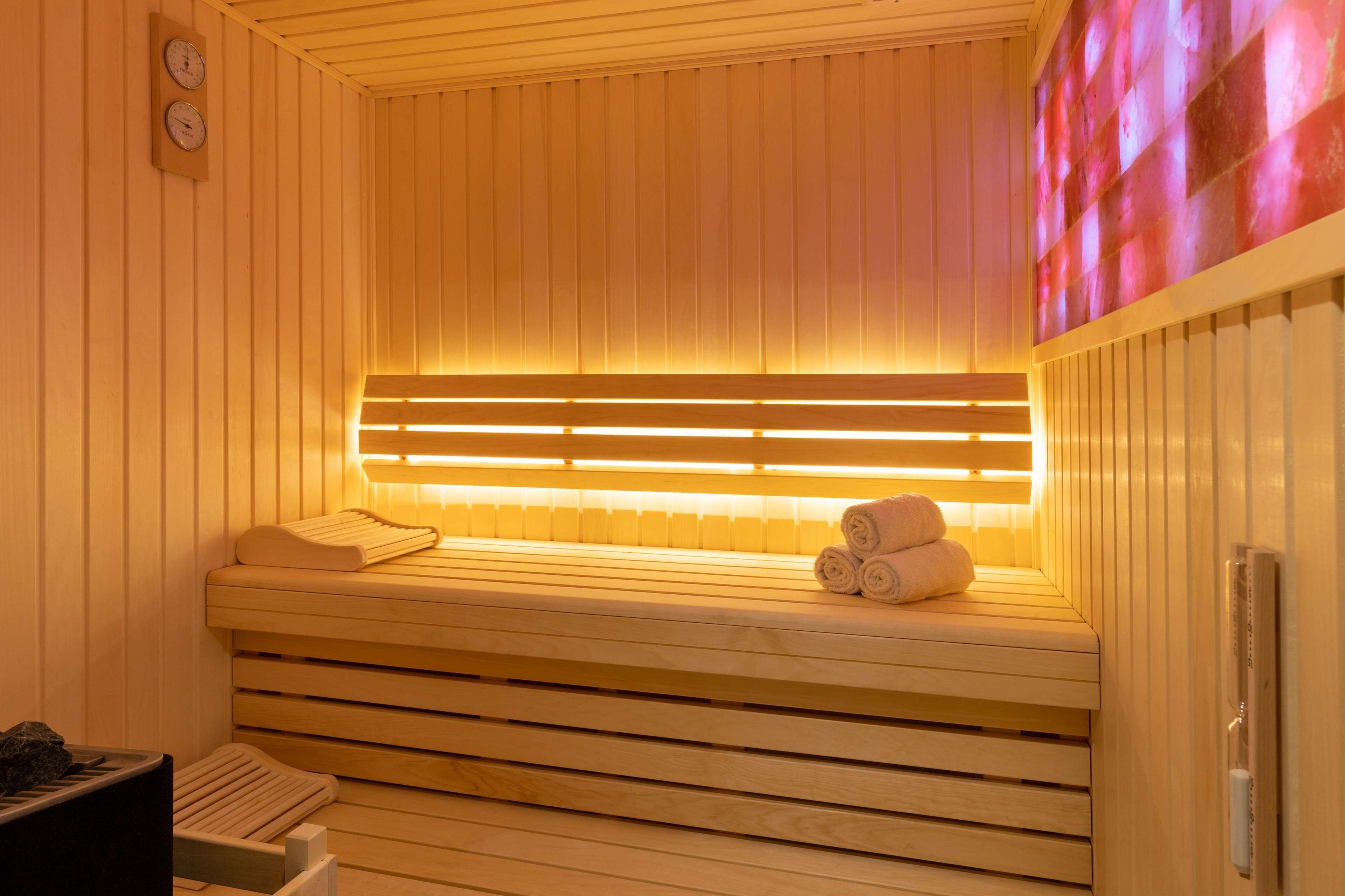 Una sauna con bancos de madera, calentador y toallas.
