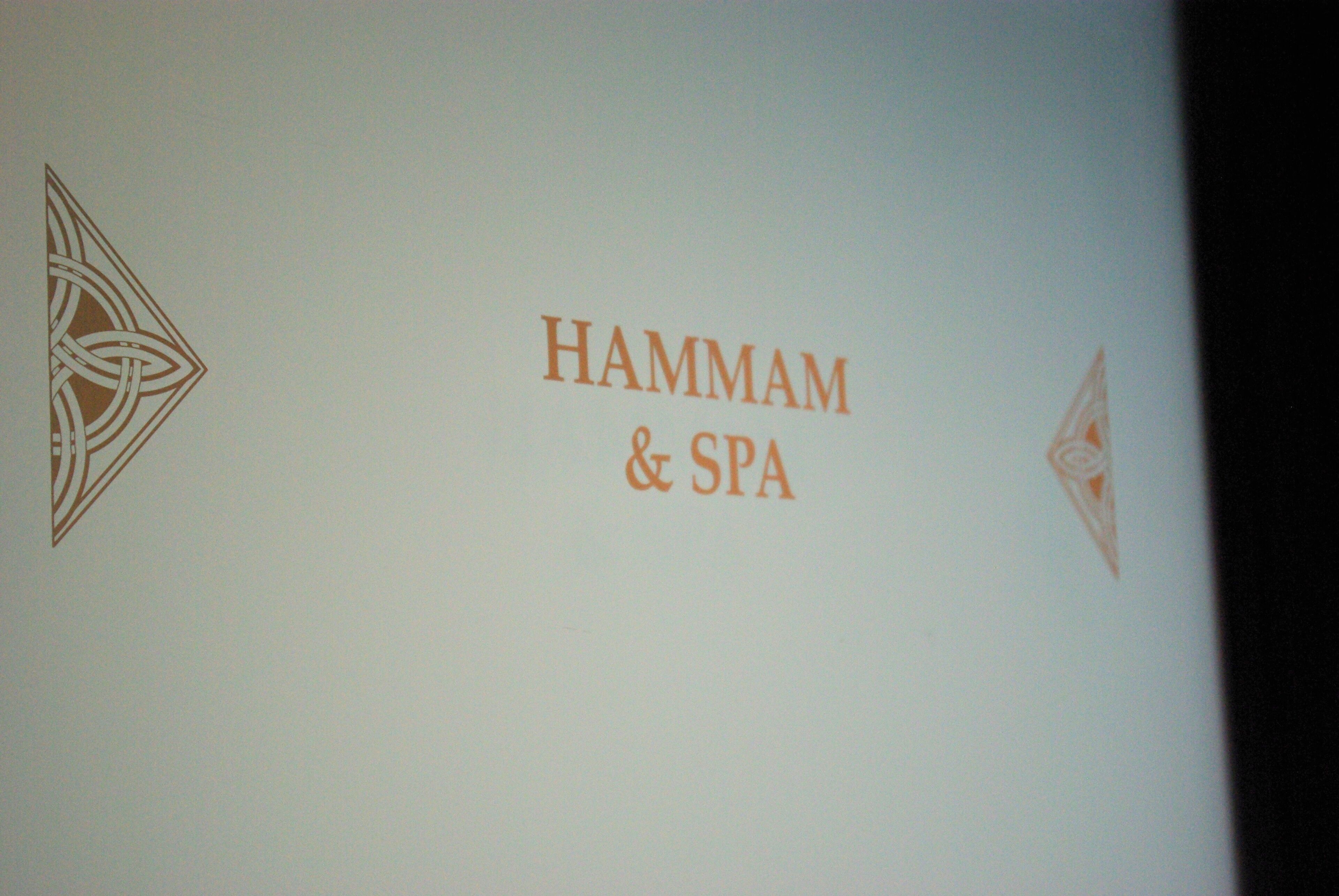 Letrero con el texto 'HAMMAM & SPA' y dos símbolos decorativos.