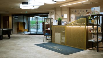 Un hall d’hôtel comprenant un comptoir d’accueil, une table de billard et une vue sur l’extérieur.