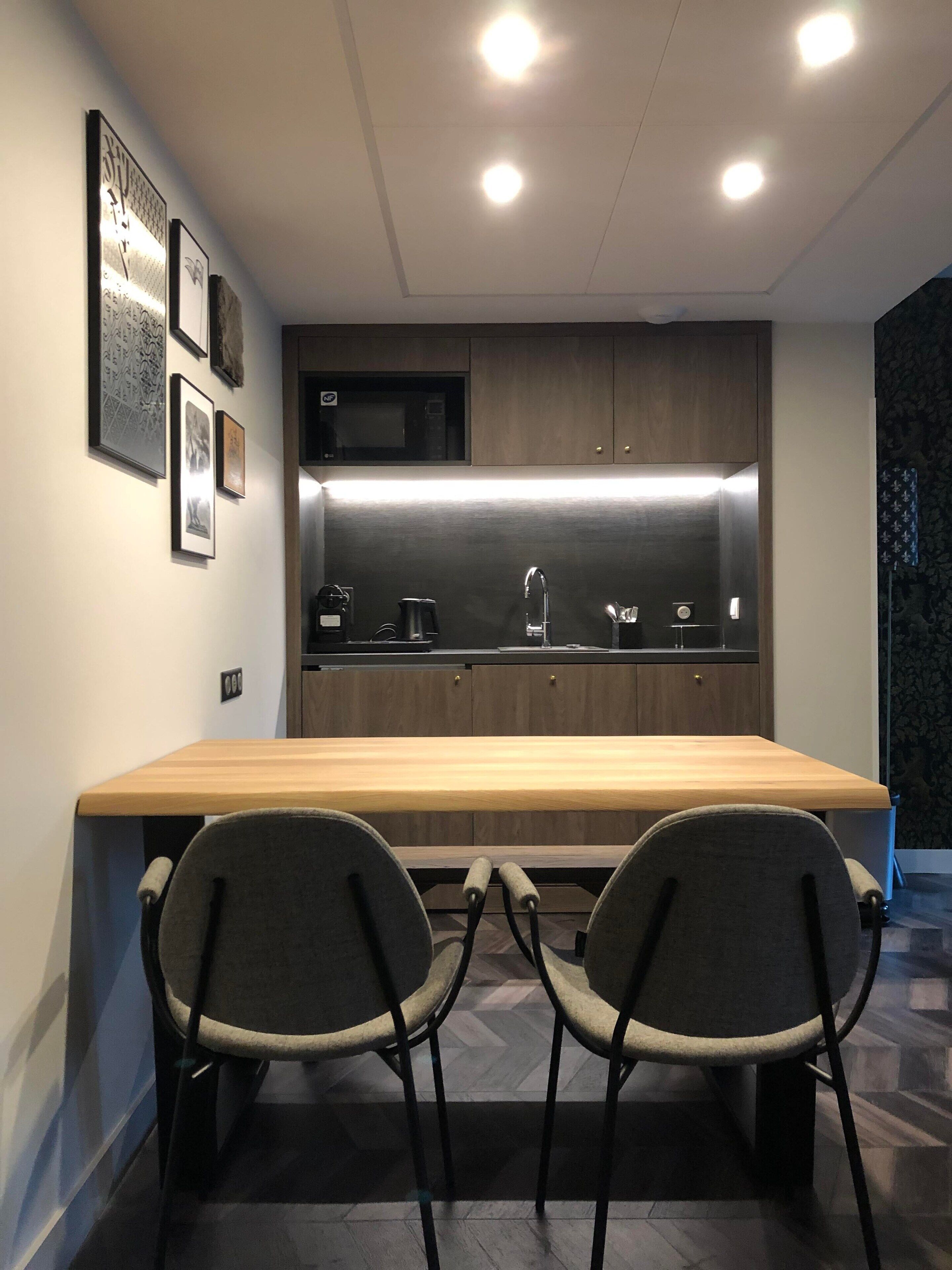 A modern kitchen with a wooden countertop, two chairs, and a built-in microwave.