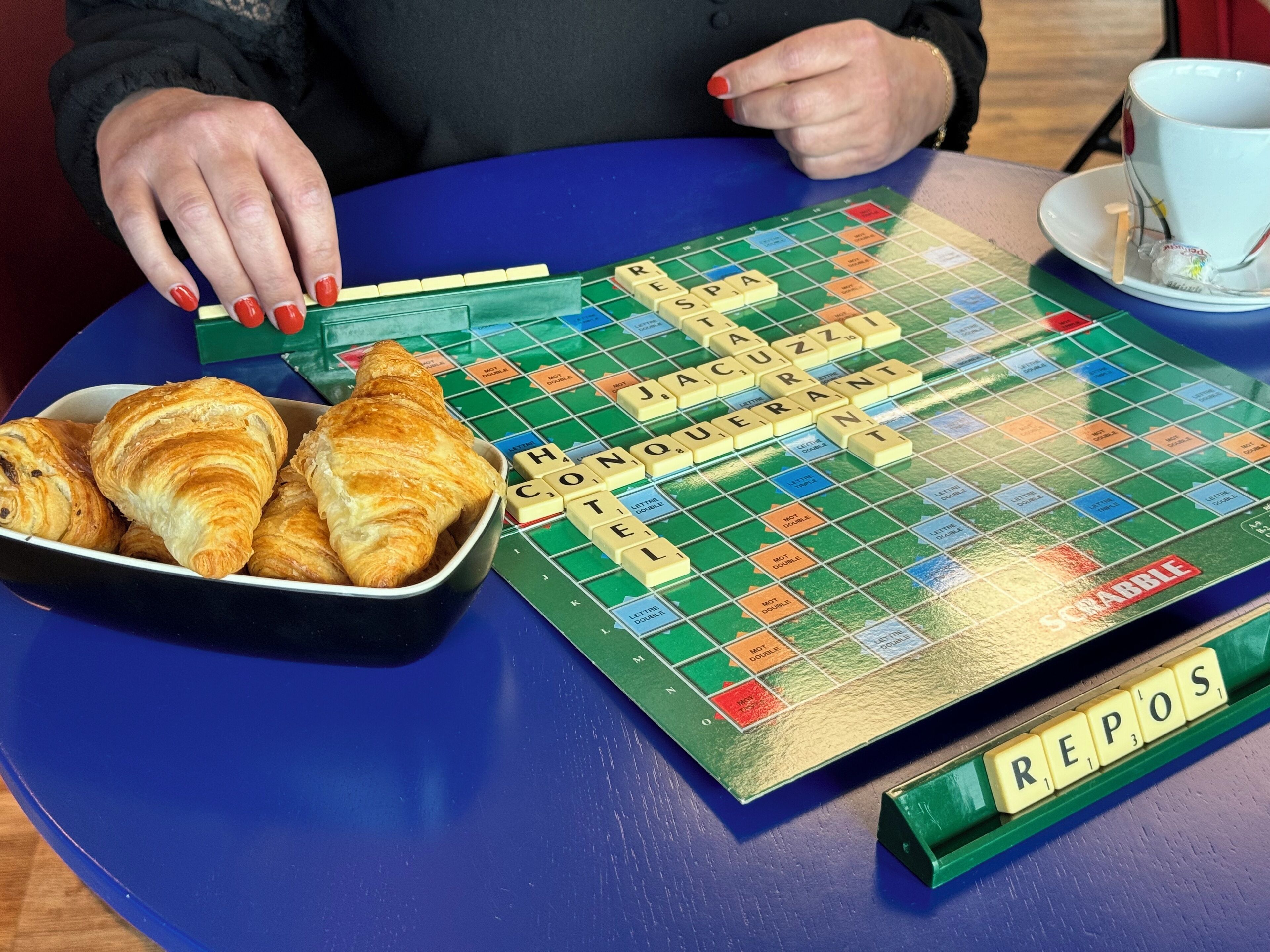 Un gioco da tavolo Scrabble con una ciotola di croissant su un tavolo blu.