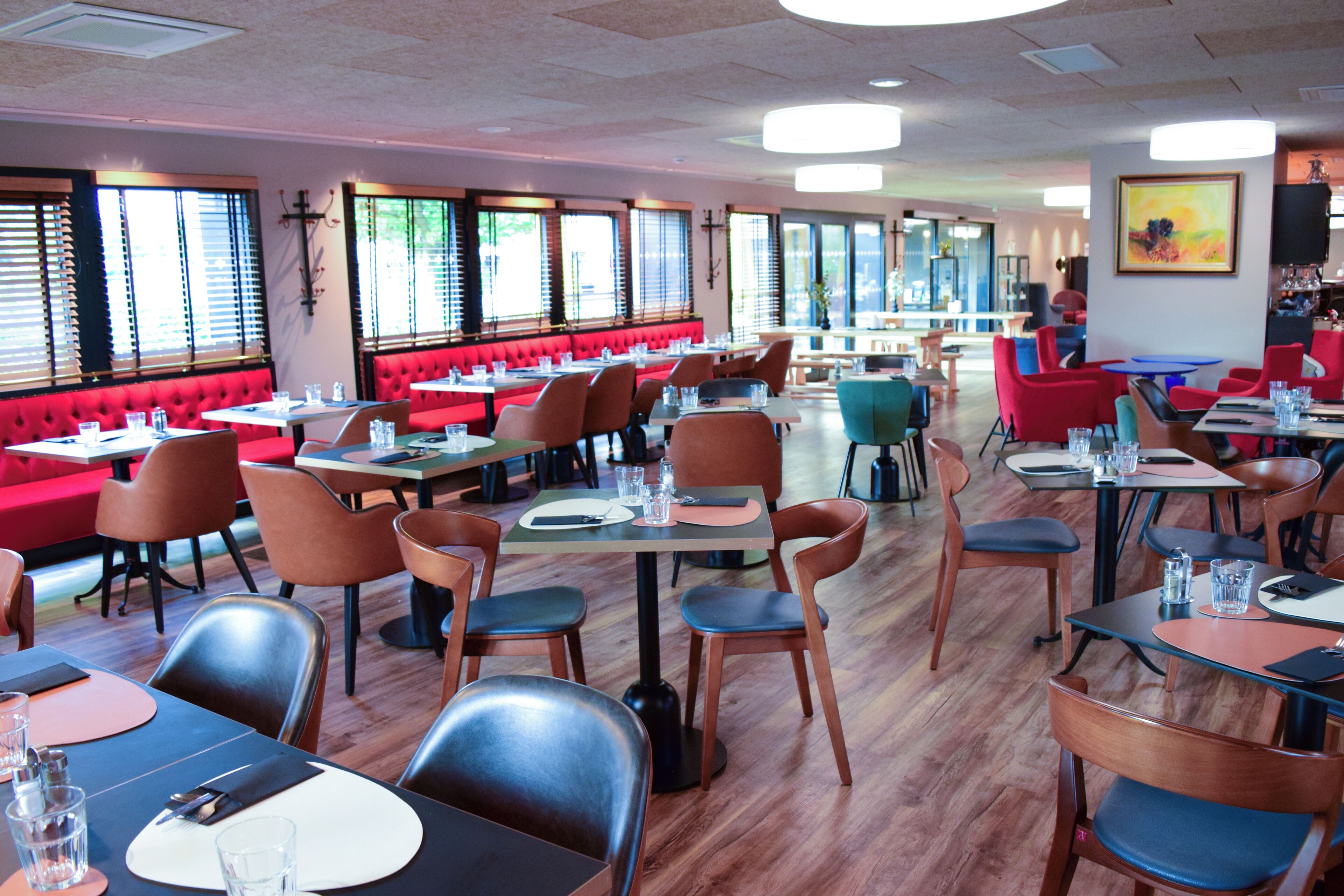 Un restaurante con cabinas y mesas rojas, suelo de madera y grandes ventanales.