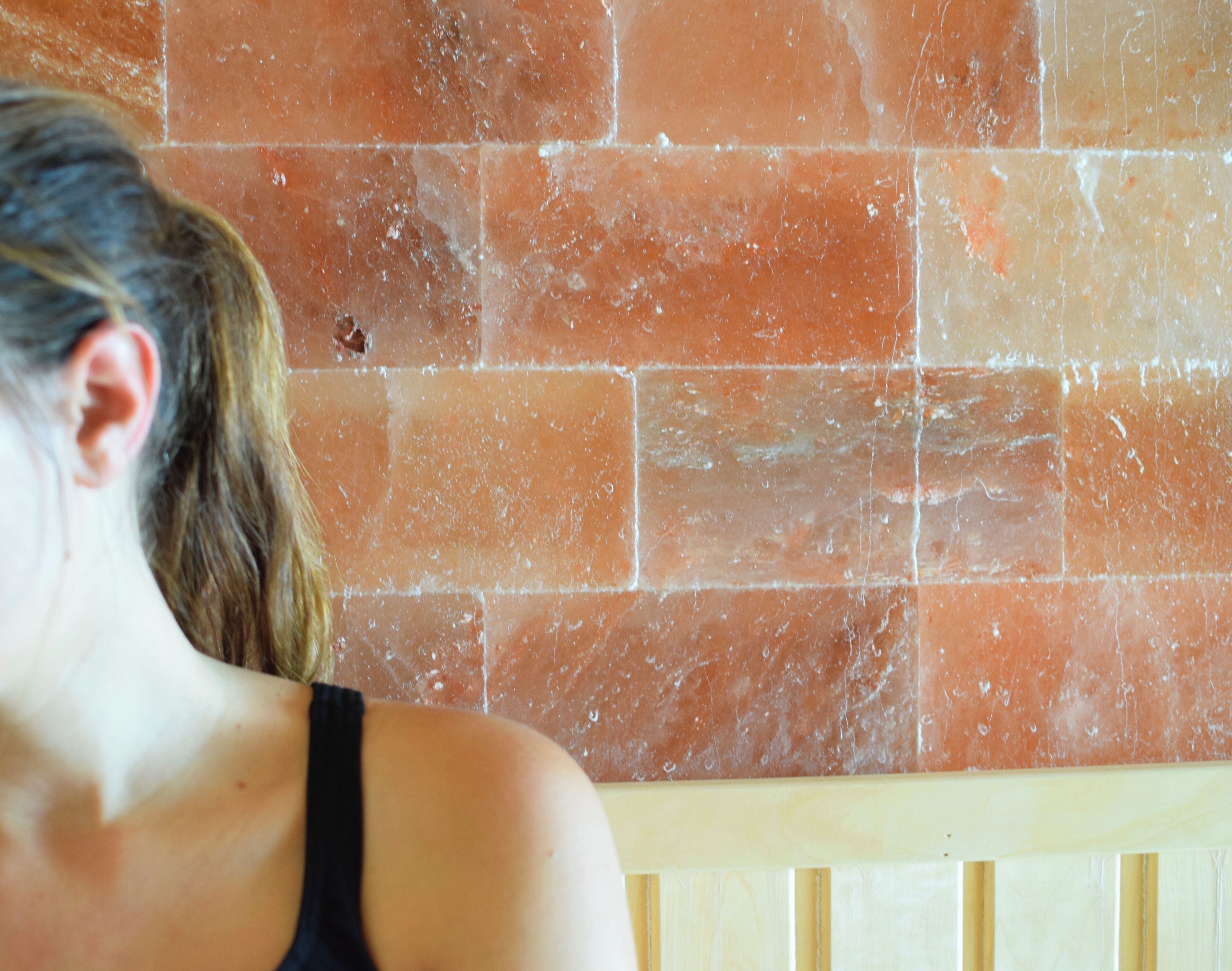 A person standing in front of a tiled wall.