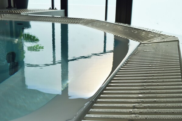 A swimming pool with a textured edge and a clear reflection. - Best Western Plus Le Conquerant Rouen Nord (Bois-Guillaume)