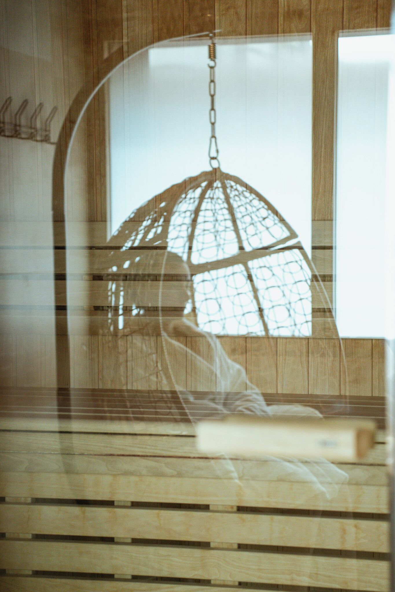A room with a hanging light fixture, wooden paneling, and a window.