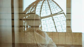 A room with a hanging light fixture, wooden paneling, and a window.