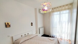 Een slaapkamer met een bed, nachtkastjes, een radiator en een raam met gordijnen.