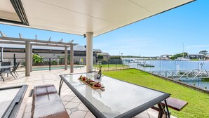 A spacious outdoor area with a pool, a dining table with food, and a view of a marina with boats. - Nirvana Waters - Absolute Waterfront Escape with Private Pontoon & Pool - Holiday Yamba (YAMBA)