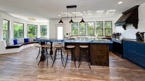 Una cocina amplia con una isla grande, taburetes de bar y una zona de estar integrada con vistas al exterior.