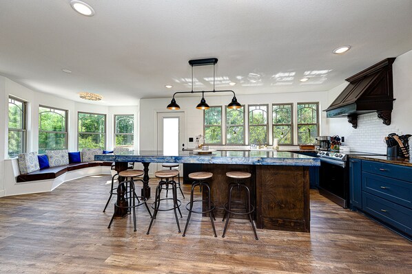Una cocina amplia con una isla grande, taburetes de bar y una zona de estar integrada con vistas al exterior.