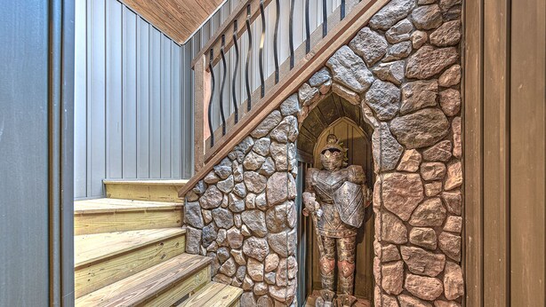 Una escalera de madera con un muro de piedra y una estatua de un caballero.