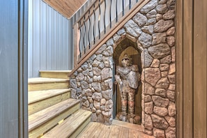 Una escalera de madera con un muro de piedra y una estatua de un caballero.