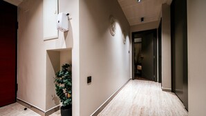 A hallway with a potted plant, a hand sanitizer dispenser, and a door leading to another room. - Luxury Rooms VINDEMIÆ (Zadar)