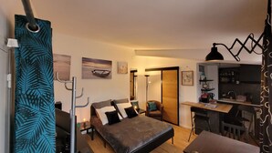 Une chambre compacte comprenant un lit, un bureau et un coin cuisine.
