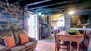 A rustic interior with a stone wall, wooden furniture, and a stone fireplace.