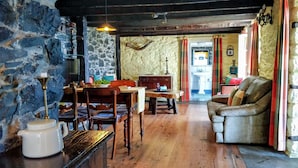 A rustic interior with stone walls, wooden furniture, and a cozy fireplace.