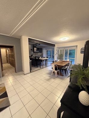 A modern kitchen with a dining area, large windows, and a view of the outdoors.
