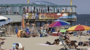 Una playa con gente tomando el sol y descansando bajo sombrillas.