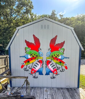 Un cobertizo de madera con un mural de dos peces coloridos en la pared.