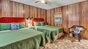 A room with two beds, wooden walls, a ceiling fan, a poster, and a chair with a sign. - Crappie Cabin - Room 5 (Wood County)