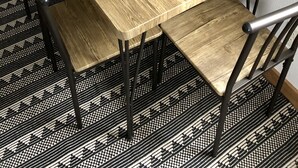 Une table de salle à manger rectangulaire en bois, dotée d’un vernis naturel, accompagnée de chaises en métal noir au design épuré.