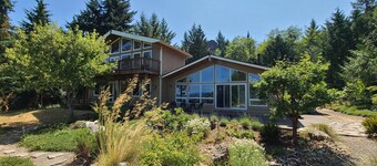 Modern retreat with serene canal, forest, and mountain views.
