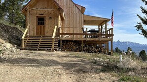 Une cabane en bois avec une véranda, une cheminée et une vue sur les montagnes.
