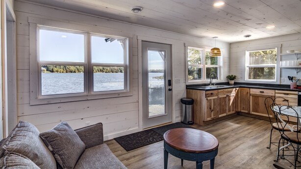 A spacious kitchen with large windows, wooden cabinets, and a view of a lake. - Cozy new cabin on Lac Courte Oreilles!! (Hayward)