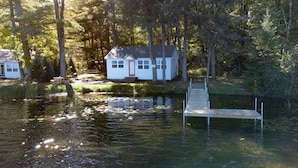 A cabin with a dock extending into a calm lake, surrounded by dense forest. - Cozy new cabin on Lac Courte Oreilles!! (Hayward)