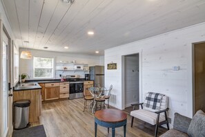 A modern kitchen with wooden cabinets, a stainless steel sink, and a dining area with a round table and metal chairs.