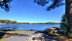 A lakeside picnic area with a fire pit, picnic table, and benches. - Cozy new cabin on Lac Courte Oreilles!! (Hayward)