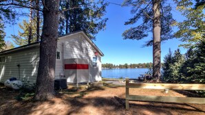 A cabin with a dock extending into a lake, surrounded by trees. - Cozy new cabin on Lac Courte Oreilles!! (Hayward)
