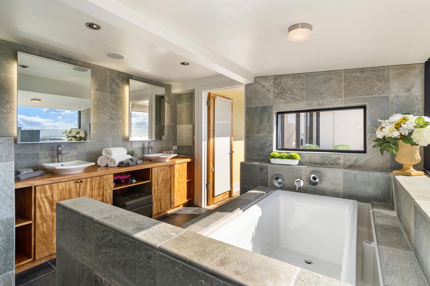 A modern bathroom with a large bathtub, a vanity with a sink, and a mirror.
