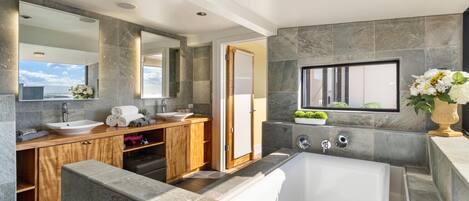 A modern bathroom with a large bathtub, a vanity with a sink, and a mirror.