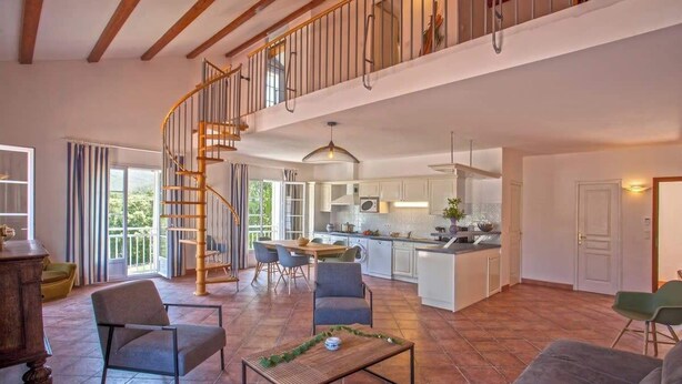 A spacious living area with a high ceiling, a spiral staircase, a kitchen, and a dining area. - Casa Catarelli. (Farinole)