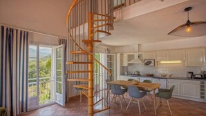 A spacious kitchen with a wooden spiral staircase, large windows, and a dining area. - Casa Catarelli. (Farinole)