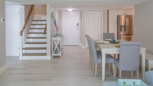 A modern kitchen with stainless steel appliances, a dining area with a table and chairs, and a staircase leading to another level.