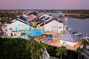A waterfront hotel with multiple buildings, outdoor seating areas, and a pool.