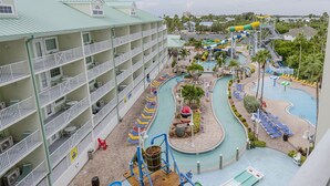 Un hotel con varios balcones, una zona de piscina con toboganes y un parque acuático.