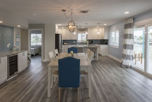 Enjoy meals in this well-lit kitchen with a central island, white cabinetry, and a large window offering a view of the outdoors.