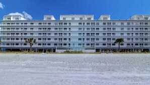 Un hotel de varios pisos con fachada plana, numerosas ventanas y vista al mar.