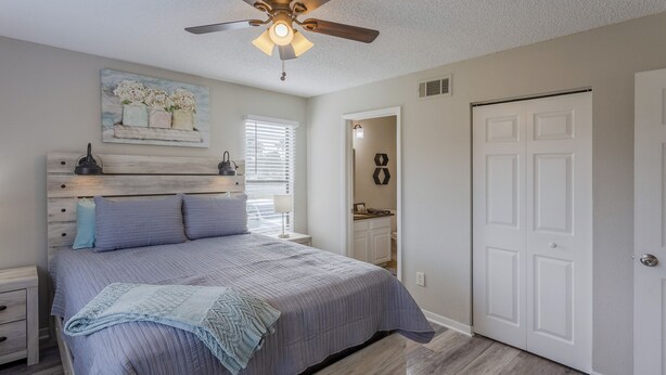 A bedroom with a bed, nightstands, a ceiling fan, a door, and a window. - La Casa Del Mar 604 Star5vacations (Dunedin)