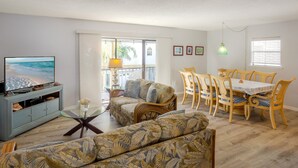 A living room with a television, sofa, dining table, and chairs. - Beautiful Seashell/ Pool Star5vacations (Indian Shores)