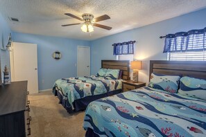 A bedroom with two beds, a ceiling fan, a nightstand, a lamp, and a window with blinds. - Beautiful Seashell/ Pool Star5vacations (Indian Shores)