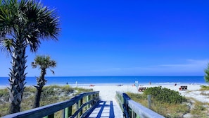 A wooden boardwalk leading to a beach with palm trees and a clear blue sky. - Beautiful Seashell/ Pool Star5vacations (Indian Shores)