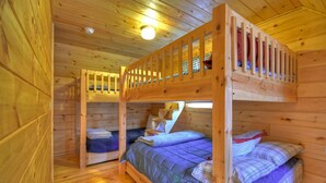 Eine Holzhütte mit Etagenbetten, einem roten Teppich und einem Holztisch.