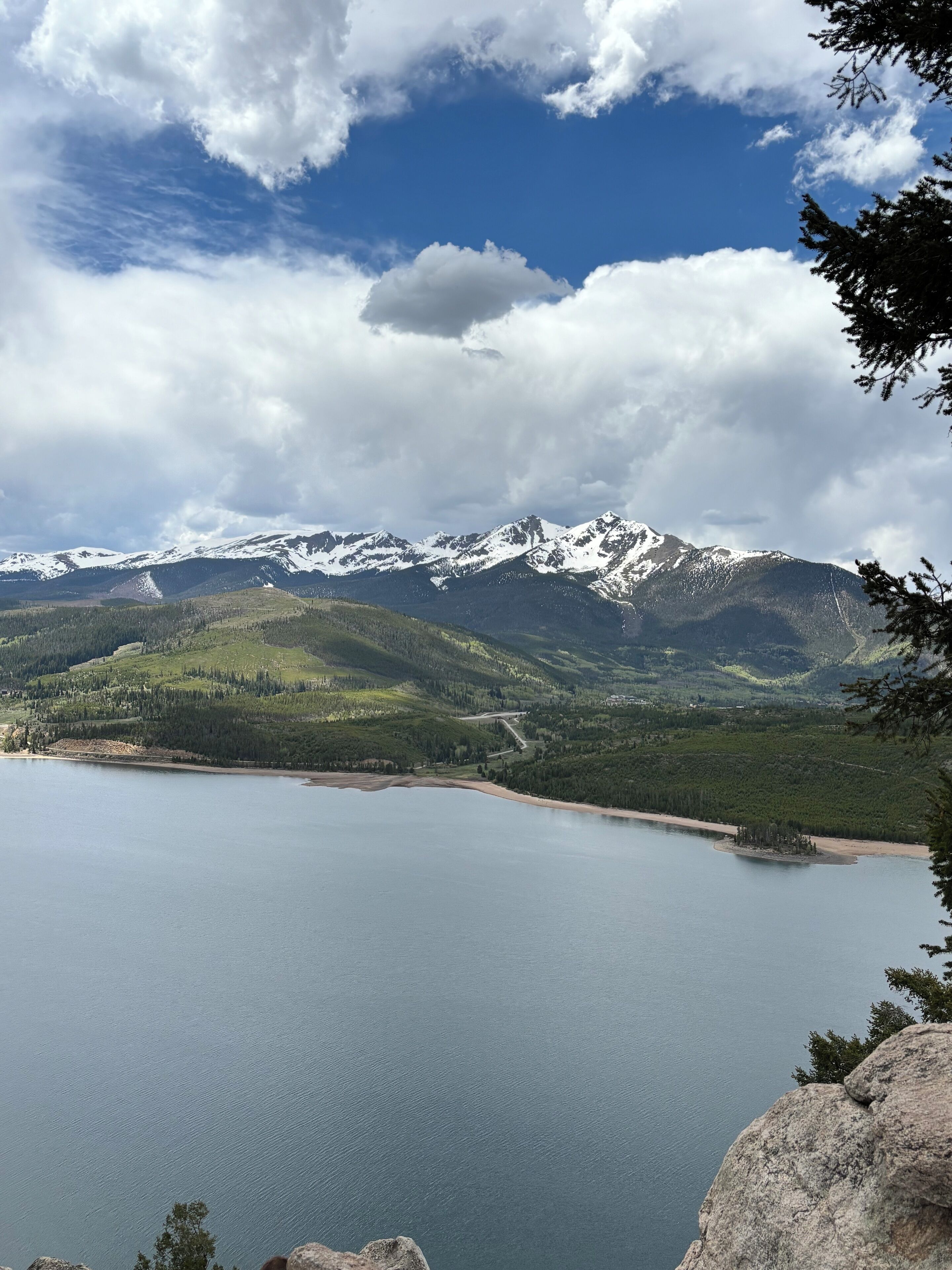 A lake surrounded by mountains with snow-capped peaks and a clear sky.