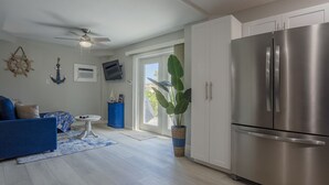 Eine moderne Küche mit einem Edelstahlkühlschrank, einer Essecke mit einem blauen Sofa und einem Deckenventilator.